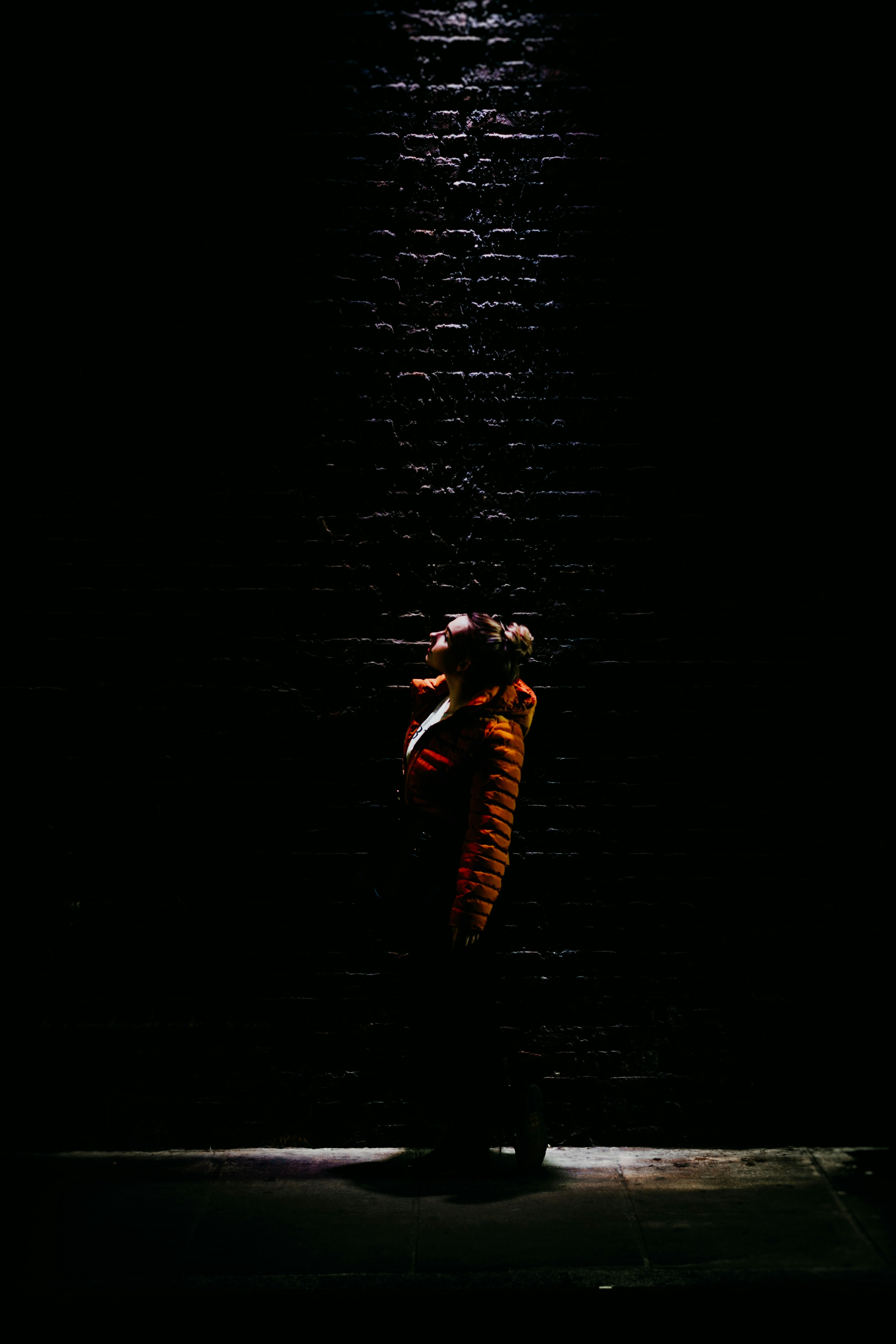 woman wearing orange bubble jacket standing while looking up